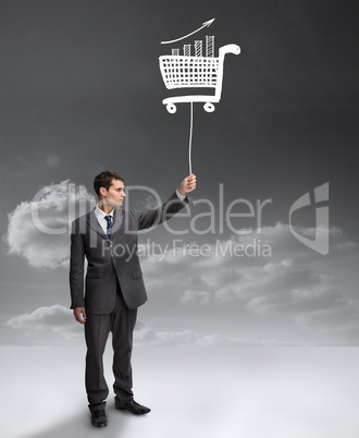 Businessman holding a floating shopping cart