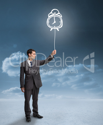 Businessman holding a floating alarm clock