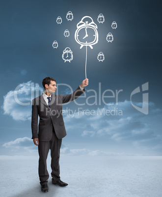 Businessman holding a floating alarm clocks