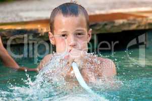 Boy playing with water hose in pool