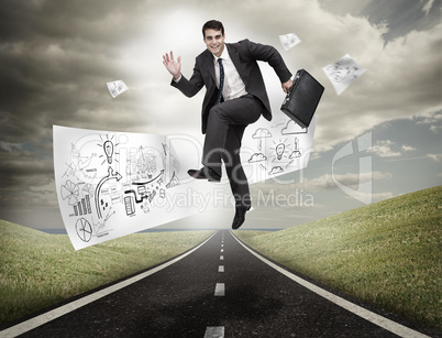 Businessman jumping on a road with drawings floating