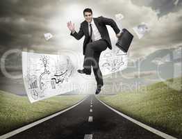 Businessman jumping on a road with drawings floating
