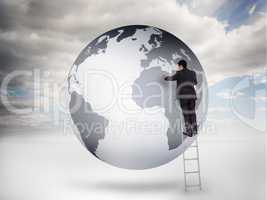 Businessman on a ladder drawing on a planet