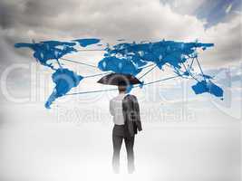 Businessman with an umbrella looking at a world map