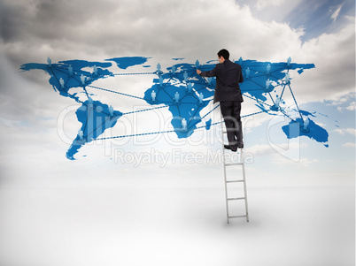Businessman standing on a ladder drawing a world map