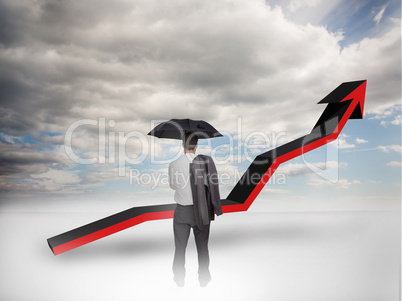 Businessman under an umbrella looking at a red arrow