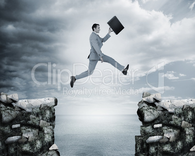 Businessman jumping a gap between cliffs