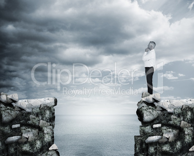 Businessman thinking at the edge of a cliff