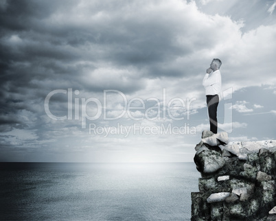 Thoughtful businessman standing at the edge of a cliff