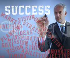 Businessman writing various words about success with a marker