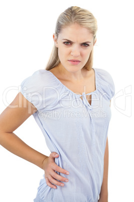 Unsmiling blonde woman has pain in lower back