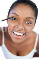 Smiling woman putting mascara on her eyelash