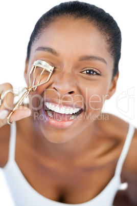 Smiling woman using curler for her eyelash