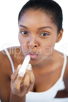 Young woman putting lip balm on her lips