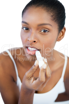 Pretty woman putting lip balm on her lips