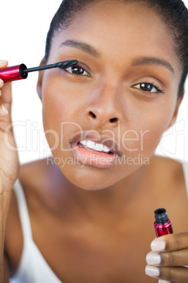 Concentrated woman using mascara for her eyelashes