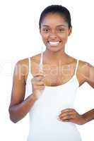 Smiling woman with hand on hip holding her toothbrush