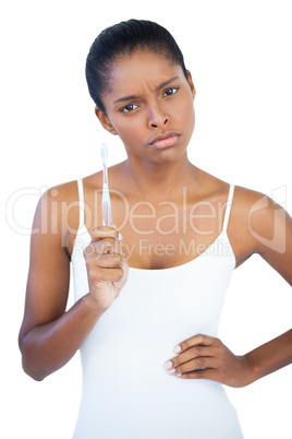 Serious woman with hand on hip holding her toothbrush