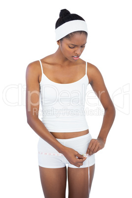 Unhappy woman measuring her waist