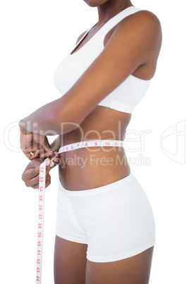Young woman measuring her waist during diet