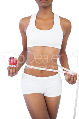 Woman holding apple and measuring her waist