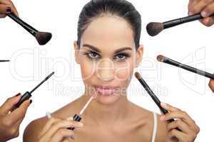 Glamorous woman encircled by make up brushes