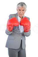Serious businesswoman standing with her boxing gloves