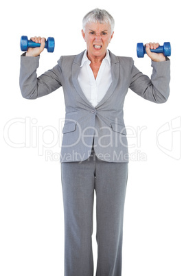 Concentrated businesswoman holding dumbbells