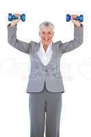 Smiling businesswoman holding dumbbells