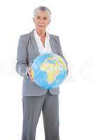 Serious businesswoman holding globe