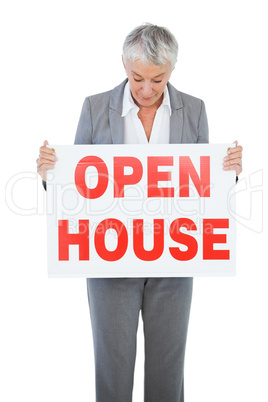 Estate agent holding and looking at sign for open house
