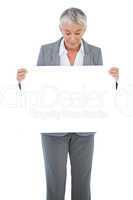 Businesswoman holding and looking at blank sign on white backgro