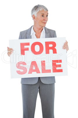 Estate agent holding sign for sale and looking away