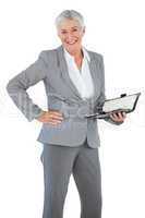 Smiling businesswoman holding diary with her hand on hip