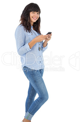 Happy brunette with her mobile phone texting a message