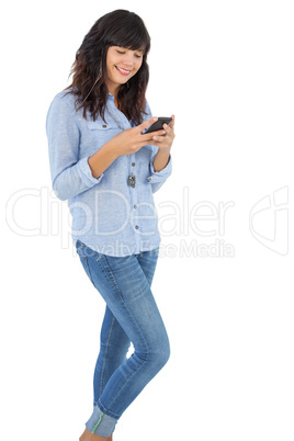 Smiling brunette with her mobile phone texting a message