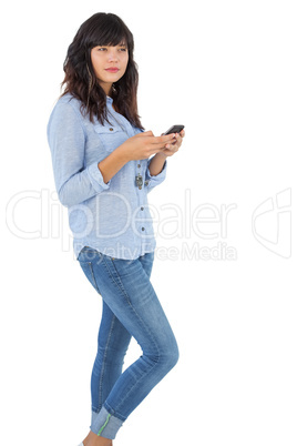 Thinking brunette with her mobile phone texting a message