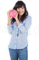 Smiling young woman shaking her piggy bank