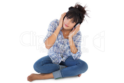 Cute young woman sitting on the floor listening to music