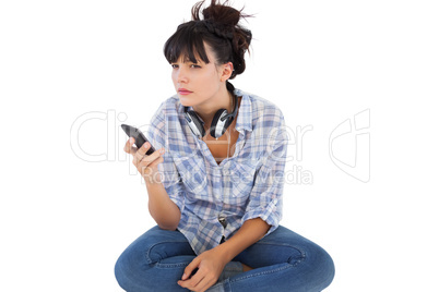 Young woman sitting on the floor with headphones holding her mob
