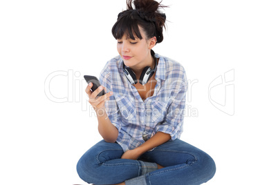 Smiling young woman sitting on the floor with headphones holding