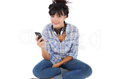 Happy young woman sitting on the floor with headphones holding h