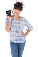 Smiling beautiful woman with her hand on hip and holding camera