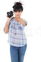 Serious woman holding camera and pointing her finger