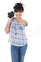 Smiling woman holding camera and pointing her finger