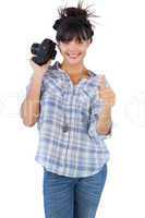 Woman holding camera and giving thumb up