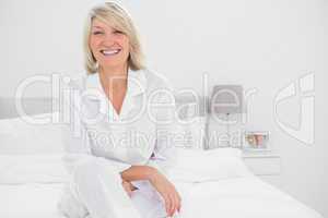 Happy woman sitting cross legged  in her bedroom