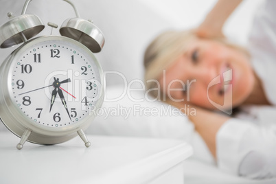 Alarm clock annoying blonde woman in bed