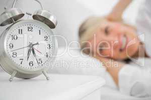 Alarm clock annoying blonde woman in bed