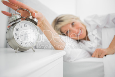 Blonde woman turning off alarm clock